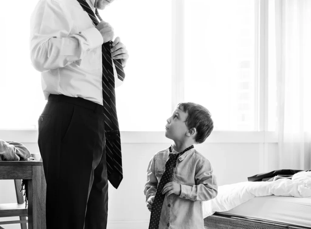 Father tying his tie next to his young son in a matching tie